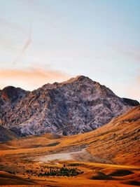 Sunset on gran sasso mountains with pink clouds and red fields in italy