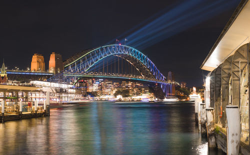 Illuminated sydney harbor bridge over river at night