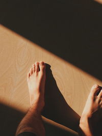 Low section of woman relaxing on hardwood floor