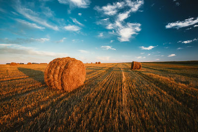 Hay bales on field against sky