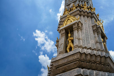 Low angle view of golden guard statue on pagoda at wat pho against sky