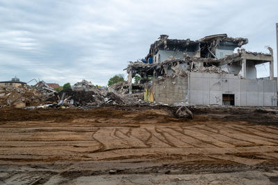 Low angle view of abandoned house on rock against sky