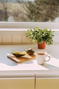 Close-up of black coffee and avocado by window