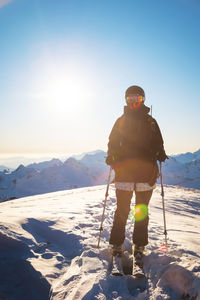 Happy woman in a ski suit and helmet stands in the mountains against the backdrop of a mountain