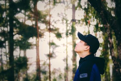 Man looking up against trees in forest