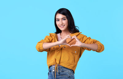 Portrait of a smiling young woman against blue background