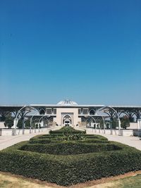 Garden by building against clear blue sky