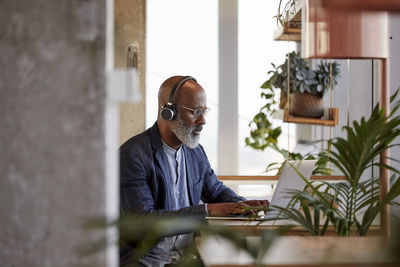 Mature male freelancer using laptop while sitting at table and working from home