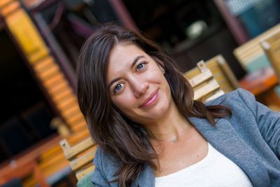 Close-up portrait of young woman smiling while sitting at sidewalk cafe