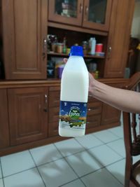 Midsection of woman holding glass bottle at home