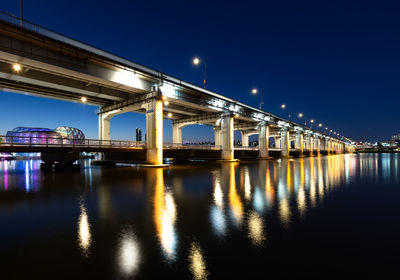 Illuminated bridge over river at night