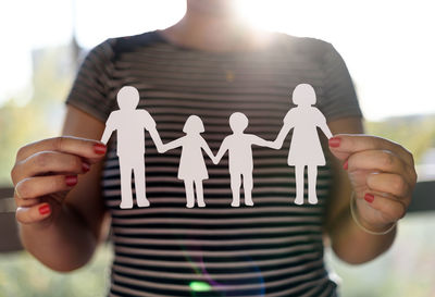 Midsection of woman holding hands standing against blurred background