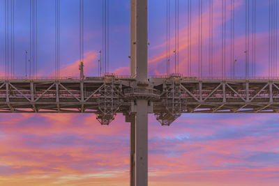 Close-up on the pillar of the rainbow bridge suspended in a double layer against a sunset sky.