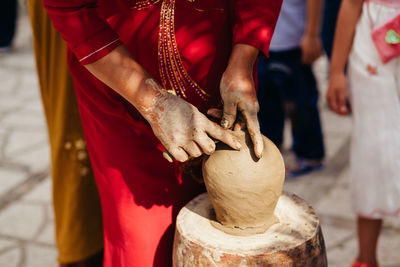 Midsection of woman making pot in city