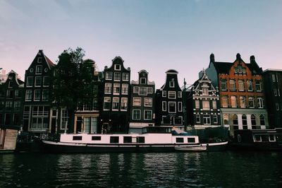 Boats moored in river with buildings in background