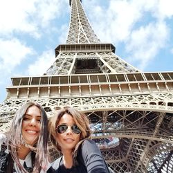Low angle portrait of smiling friends standing against eiffel tower