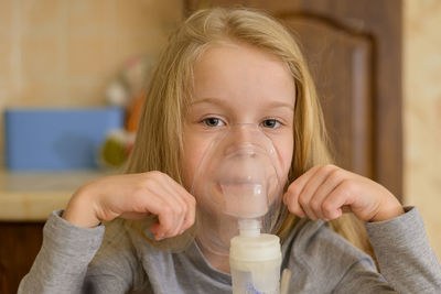 A sick child makes inhalation with a nebulizer at home, he holds a mask from which steam. the child