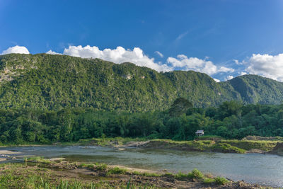 Scenic view of river by mountains against sky