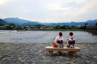 Men on riverbank against sky