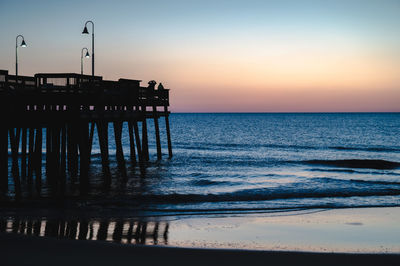 Scenic view of sea against sky during sunset by pier