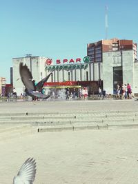 Group of people in city against clear sky