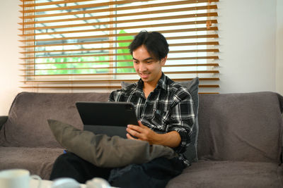 Young woman using laptop while sitting on sofa at home
