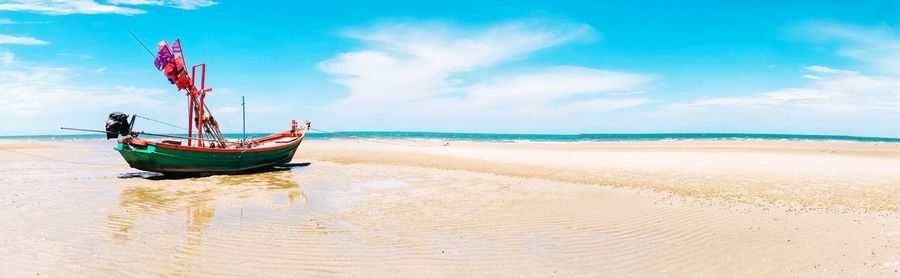 Boat moored on beach against sky