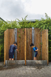 Two boys bathe in an outdoor bath before entering the pool.