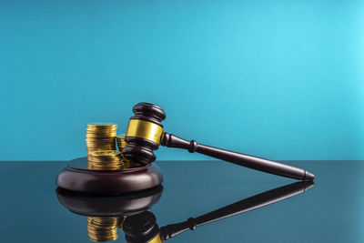 Close-up of gavel and stacked coins on table against wall