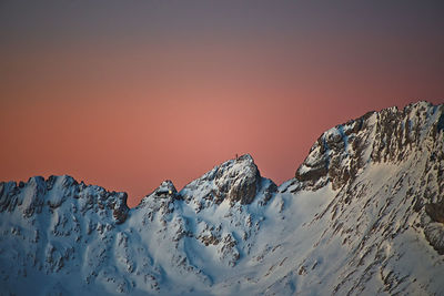 Scenic view of snowcapped mountains against clear sky during sunset