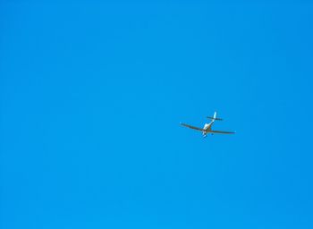 Low angle view of airplane against clear blue sky