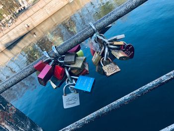 Padlocks hanging on railing by bridge