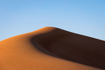 Low angle view of sand dunes against clear sky