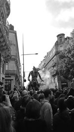 People on street amidst buildings in city against sky