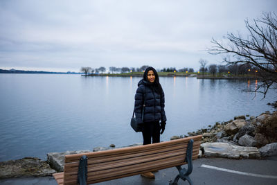 Woman standing by lake against sky