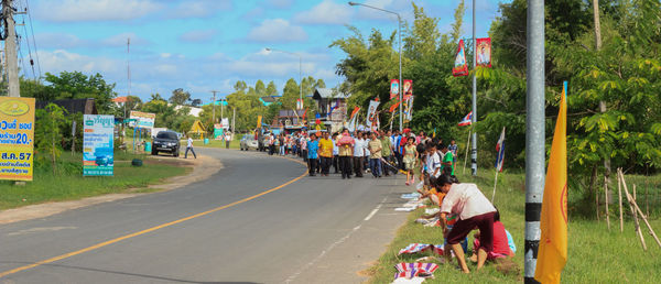 People on road by trees against sky