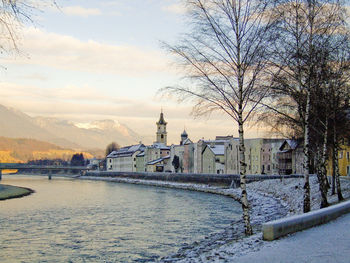 Bridge over river amidst buildings against sky during winter