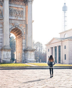 Rear view of woman walking on footpath against clear sky