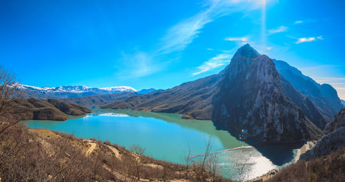 Scenic view of lake and mountains against blue sky