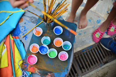 Low section of kids standing by paints and paintbrushes