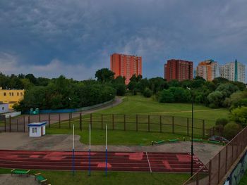 View of field by buildings against sky