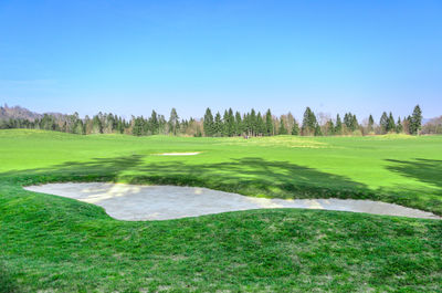 Scenic view of golf course against clear sky