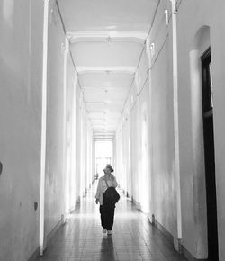 Rear view of woman walking in corridor of building