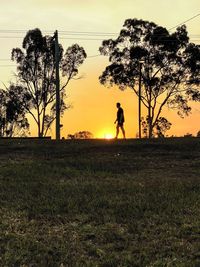 Silhouette person standing on field against sky during sunset