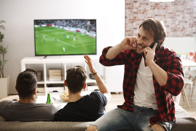 Friends watching television set at home