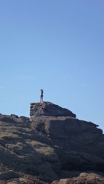 Low angle view of man on cliff against clear sky