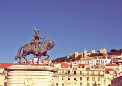 Statue in city against clear blue sky