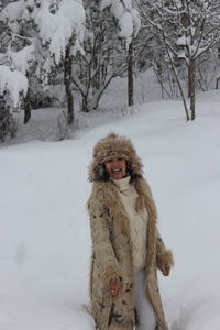 Portrait of cheerful woman standing on snow covered field