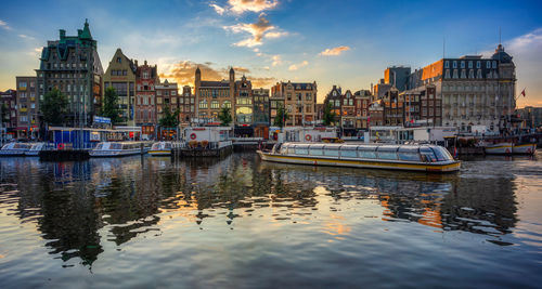 Boats moored in canal by buildings against sky in city