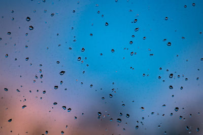 Full frame shot of wet window during monsoon at sunset